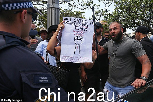 Sukkar 先生旁边的一位女士举着标语,上面写着“反天主教的偏见必须结束”,并声称基督徒是“世界上受迫害最严重的宗教团体”