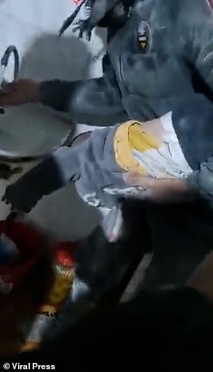 图为：在视频中，一名小男孩被救援人员从叙利亚的废墟中拉出来，地震发生在夜间