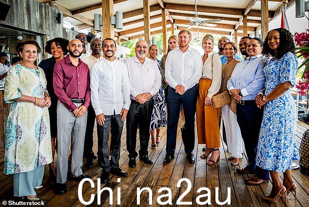 女王穿着暖色调的套装与其他人合影,享受一天的活动at St Maarten