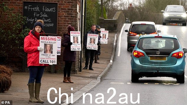 失踪妇女Nicola Bulley的朋友们在主干道上举着寻人启事海报the village in St Michael's on Wyre, Lancashire