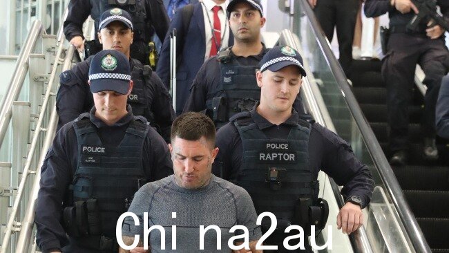 Meehan 在大量警察的护送下通过悉尼机场。图片:John Grainger。