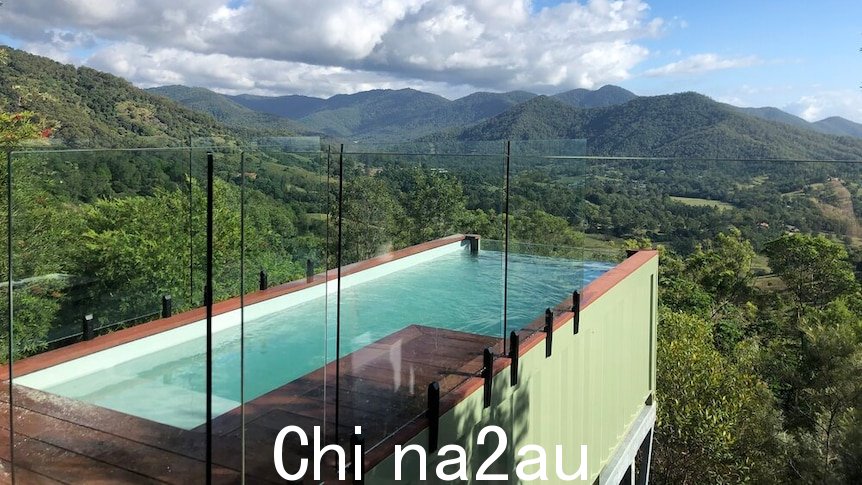 带有玻璃围栏的绿色集装箱池延伸到甲板外，俯瞰山谷。