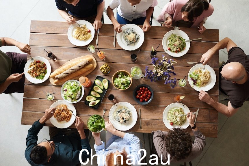 一群人围坐在摆满食物的餐桌旁的航拍照片。