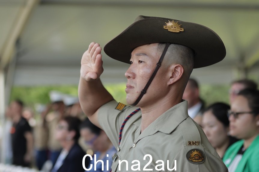 一名士兵在大帐篷下的人群中敬礼。