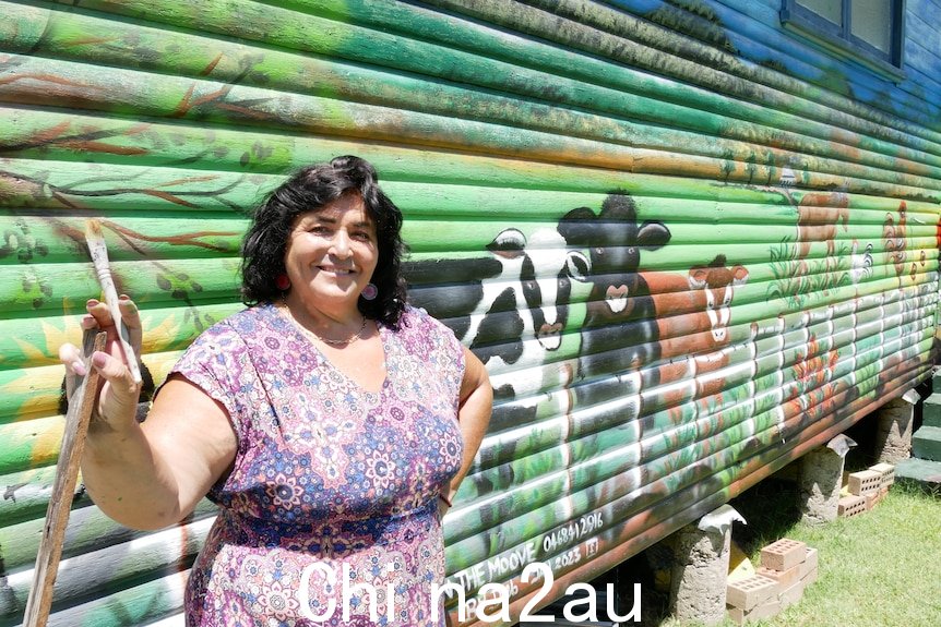 女人站在她的绿色围场奶牛壁画前。 
