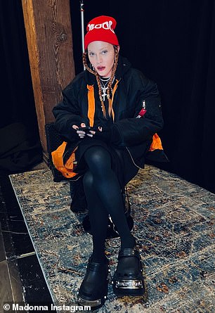 坐下:麦当娜穿了一件 Vetements 飞行员夹克,带有亮橙色衬里和羊毛兜帽
