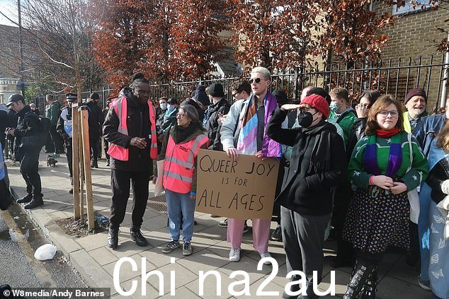 反抗议者手持旗帜和标语在街道两旁排列,看不到右翼抗议者