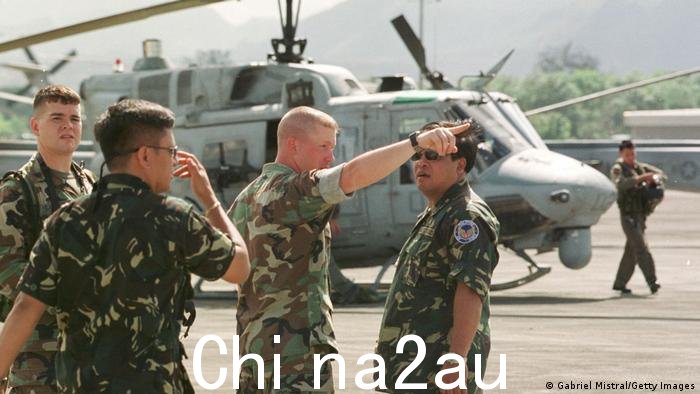 图为美军在菲律宾空军基地安吉利斯市克拉克空军基地，向一名菲律宾士兵介绍美国直升机的夜间飞行能力。