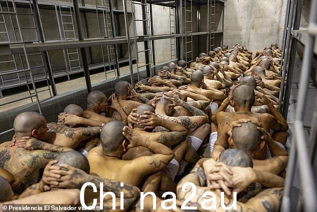 囚犯被迫三人一排穿过狭窄的走廊,双手紧扣在脑后