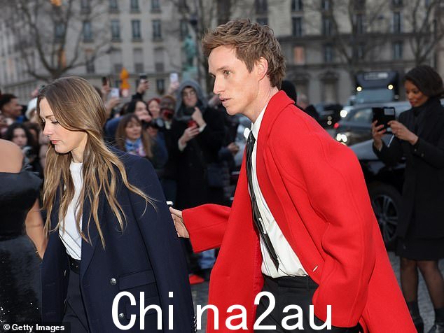 问候他们的公众:在他们身后可以看到兴奋的粉丝,人群举起手机希望能拍到明星的照片