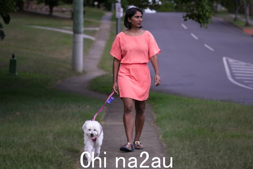 一个穿粉红色裙子的女人走在small white dog