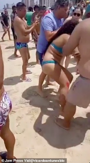 人们帮助把女孩带到海滩上,远离大海