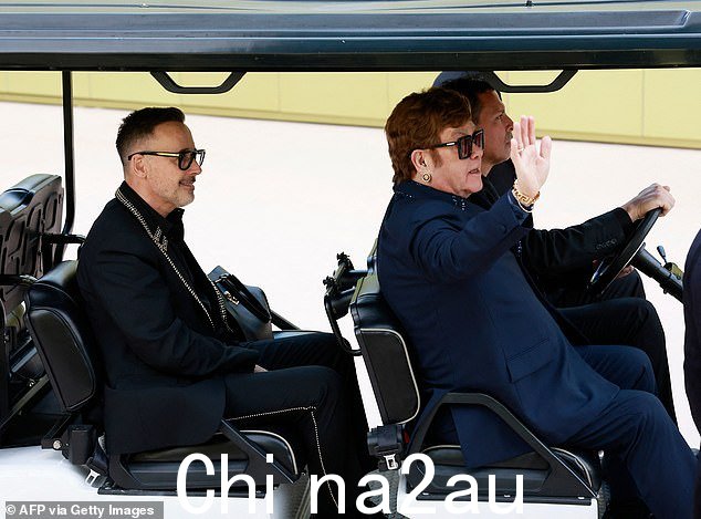 问候:Elton John 向路人挥手,而 David 坐在后座