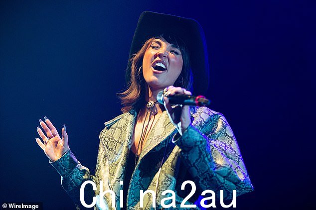 表演:她穿着喇叭形人造皮裤和黑色文胸,搭配绿色蛇皮印花夹克,看起来毫不费力地时尚
