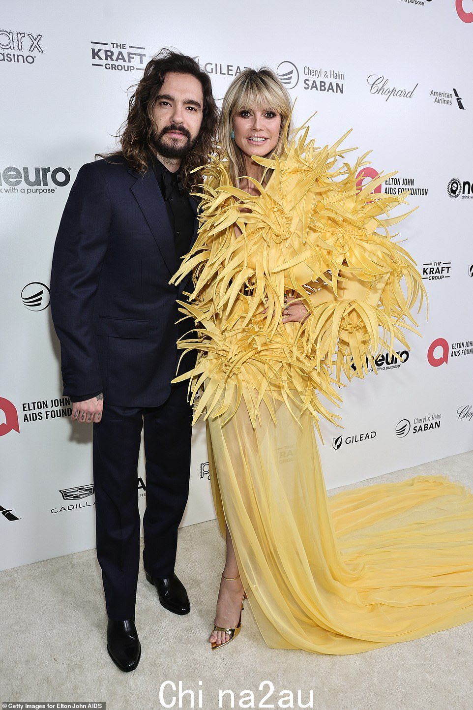 哇! Klum 和她的丈夫 Tom Kaulitz 一起参加了为 Elton John AIDS Foundation 筹集资金的狂欢,她穿着一件大胆的羽毛连衣裙和一条滚滚的半透明拖尾从人群中脱颖而出。