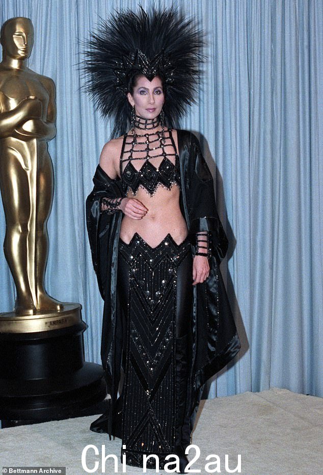 1986 年,雪儿 (Cher) 穿着耀眼的 Bob Mackie 黑色两件式上衣引起了人们的注意 - 但真正引起人们注意的是她气势磅礴的羽毛状头饰。这位歌手后来告诉纽约时报,她选择了戴上令人瞠目结舌的造型,因为她很生气自己在《面具》中的角色没有被提名。“我根本不打算去。然后他们让我出席,这些人刚刚说,“不,你不能成为我们中的一员。”然后我决定,“我要提醒他们他们不喜欢我的地方。”'她后来似乎重新然而,在接受 Film Comment