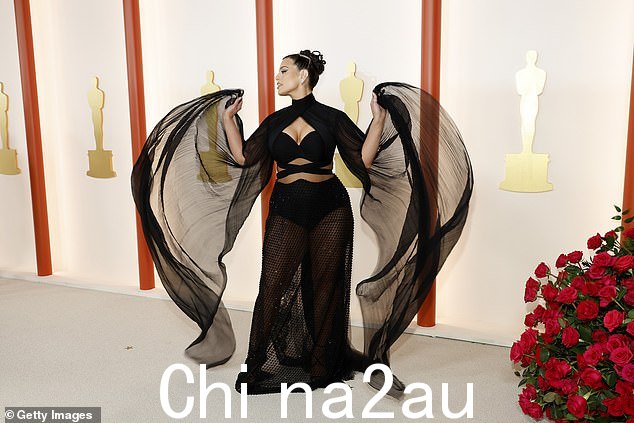 带来戏剧效果:惊心动魄的礼服在腹部采用透明面板和高领斗篷,带有戏剧性袖子,她高兴地向摄影爱好者展示了它