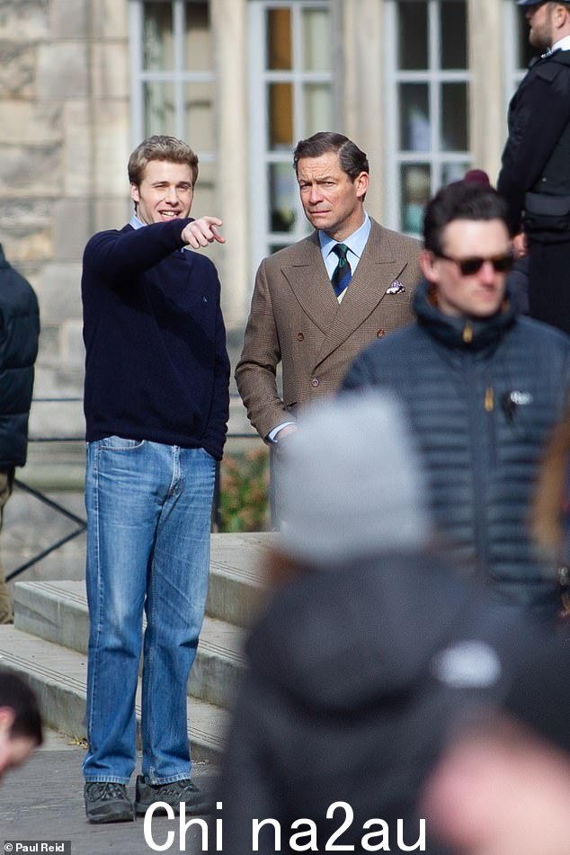 Ed McVey 身着海军蓝毛衣和牛仔裤,与 Dominic West 一起在圣安德鲁斯大学拍摄 The Crown