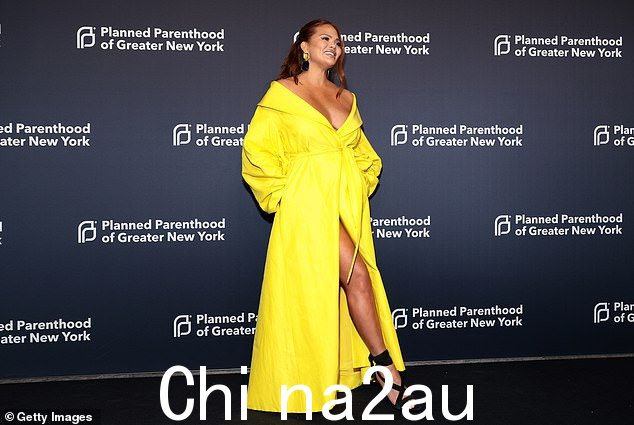 哇! Chrissy 穿着 Monique Lhuillier 设计的亮黄色深 V 大衣连衣裙,露出乳沟,露出美腿。” class=