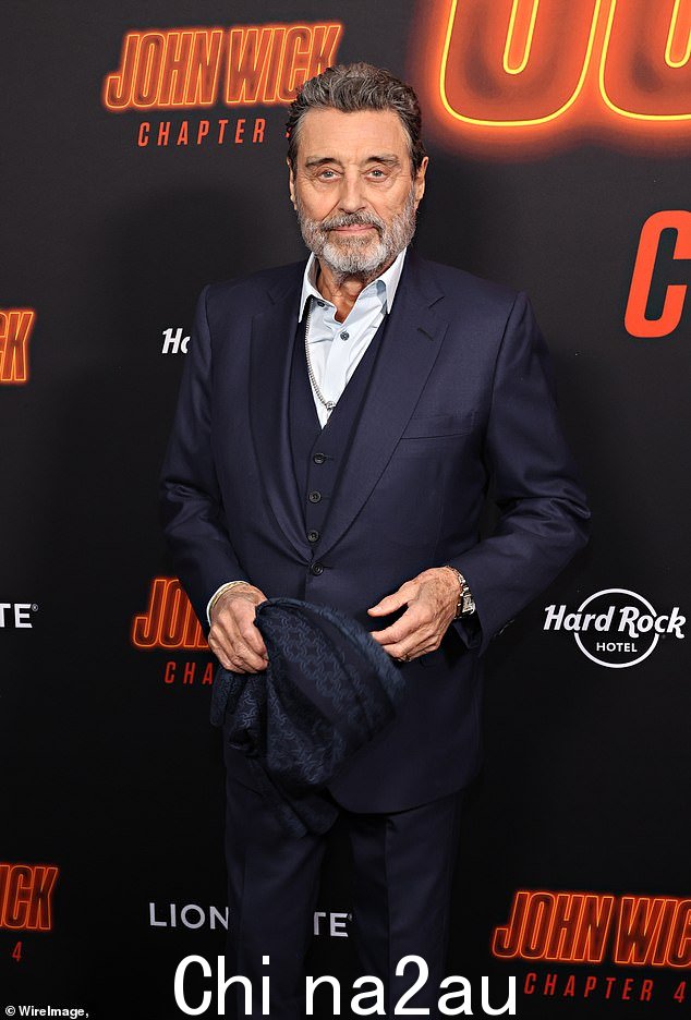 Ian McShane 穿着整洁的海军蓝西装在地毯上满脸笑容