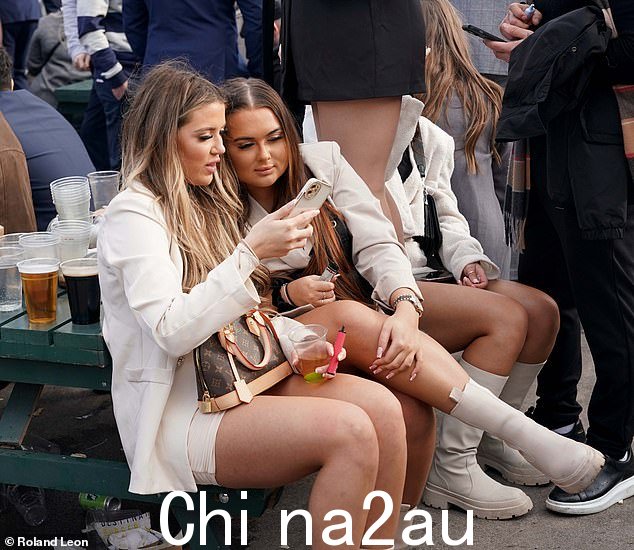 这些女孩在查看左边年轻女士的手机屏幕时看起来正在深入交谈