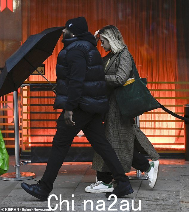 她来了:与此同时,36 岁的珍娜 (Jenna) 身边有一名保安,她躲在下面当她到达剧院时一把巨大的雨伞