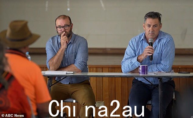 周二在 Menindee 市政厅举行的会议上，官员们在人群面前喝了一杯水