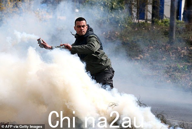 自上周四法令强制通过该措施以来,夜间骚乱不断,现在数百万人将在白天聚集 - 法国最大的机场被示威者封锁今天早上。图为:2023 年 3 月 23 日在法国东部兰斯举行的示威活动中,一名示威者手持烟雾弹