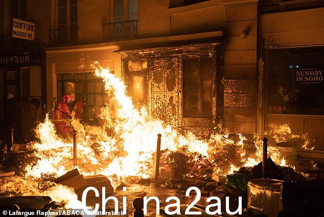 一名消防员试图扑灭抗议者在巴黎圣马克街引发的火灾