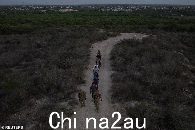 墨西哥在背景中被视为德克萨斯陆军国民警卫队星期四,士兵们在移民穿过里奥格兰德河走私到德克萨斯州罗马后引导他们