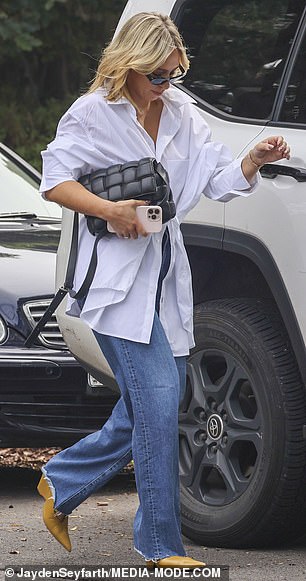 她拿着一个价值 6700 美元的 Bottega Veneta 手提包,搭配橙色尖头靴、猫眼太阳镜和价值 12,000 美元的卡地亚金色手镯,使她的造型更加完美