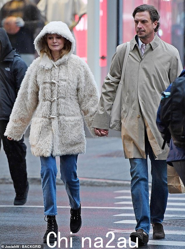 Fuzzy coat:这位 Austin Powers 明星穿着一件带兜帽的毛茸茸的白色纽扣大衣。外套垂到大腿中部,让她保持温暖和干燥