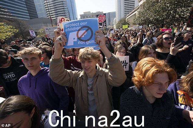 一名青少年在集会期间举起他的标语支持更严厉的枪支法,集会的目的是“结束枪支暴力”