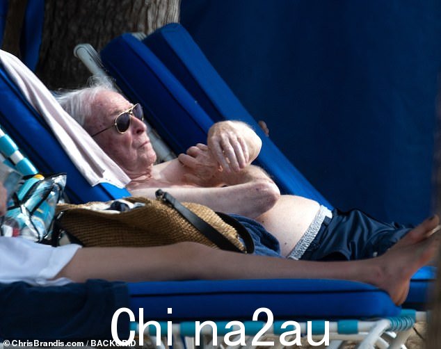 Soaking up the sun: Michael was seen heading to a deckchair with the help of his trusty walking frame and an aide before settling in to top up his tan