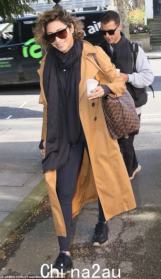 Chilled: Elsewhere Karen Hauer,40 岁,穿着棕色风衣和深色墨镜,手里拿着咖啡