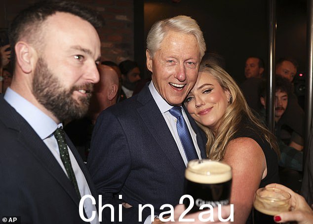 比尔·克林顿 (Bill Clinton) 昨晚去当地一家酒吧喝了一品脱吉尼斯啤酒,让北爱尔兰一座城市的当地人大吃一惊。图为:克林顿与 SDLP 领导人科勒姆·伊斯特伍德 (Colum Eastwood) 以及伊斯特伍德的妻子(左)在一起Rachael(看到拥抱前总统)