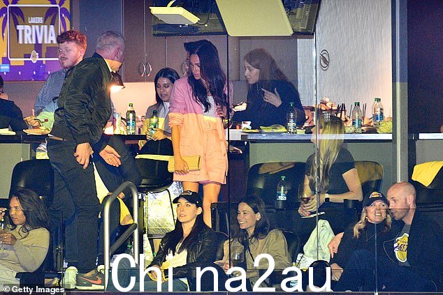 Meghan 在穿过一个小酒吧区走向她的座位时与某人聊天