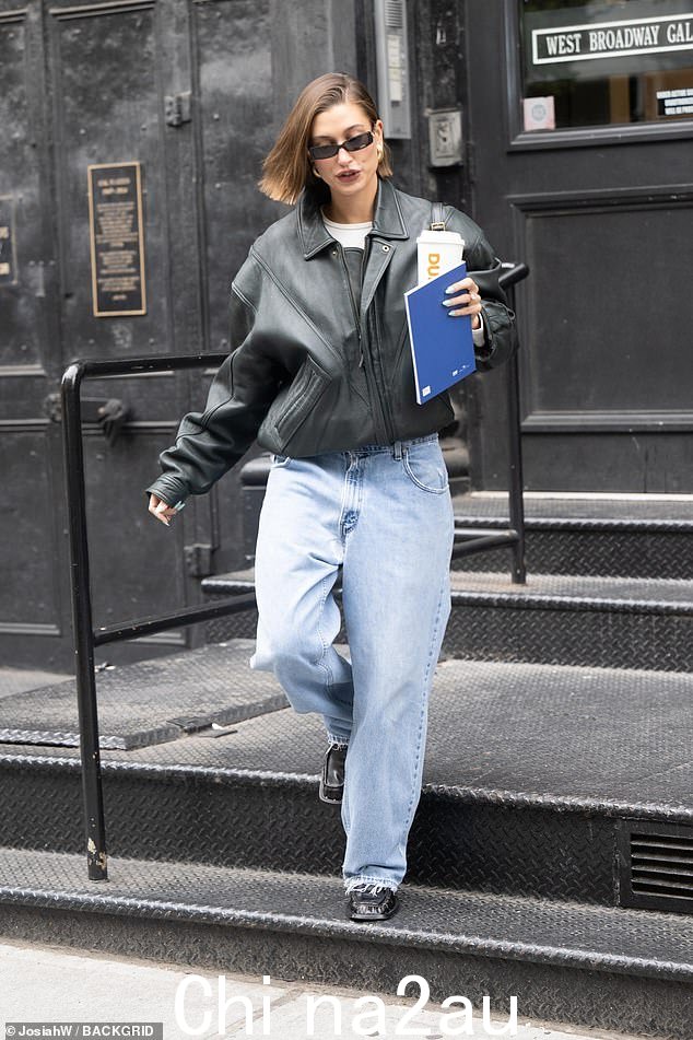 出去走走! Hailey 戴着小太阳镜,手里拿着一本蓝色的书和一个 Dunkin'