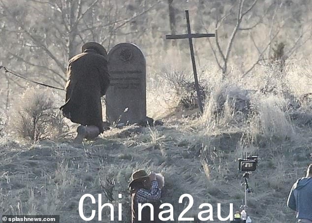 鲍德温跪在蒙大拿西部片片场的坟墓前,开始拍摄