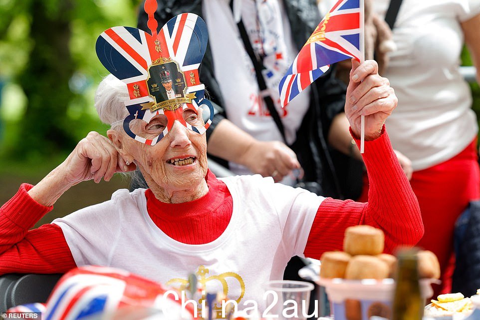 当人们用盛大的午餐庆祝英国国王查尔斯的加冕典礼时,一位女士挥舞着英国国旗
