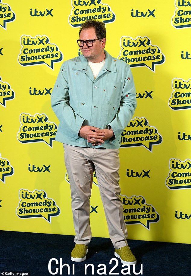 休闲造型:Alan Carr 穿着米色长裤和带有花卉图案的蓝色夹克,搭配绿色乐福鞋,看起来很时尚