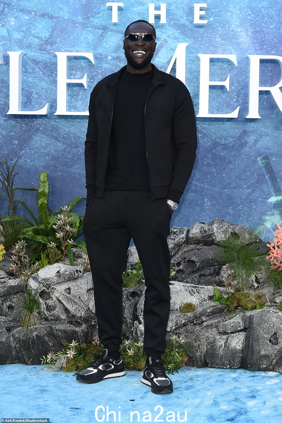 喜气洋洋:Stormzy 在放映时为快照摆姿势时剪下了一个典型的酷身材