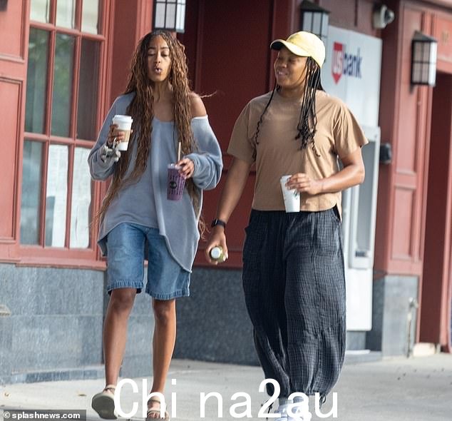 Malia 穿着穿着宽松的上衣和宽大的牛仔短裤