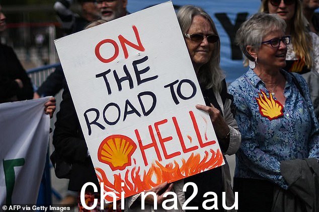 一名示威者在壳牌年度股东大会外举着写着“通往地狱之路”的标语牌