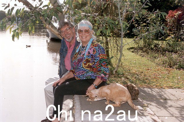 哈里斯和他的妻子把腿悬在墙边,在他们的猫旁边摆姿势拍照