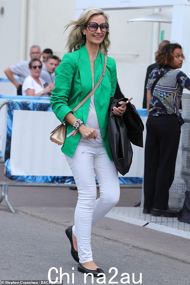 充满嫉妒的绿色：当她向路人挥手时，维多利亚身穿绿色西装外套、白色牛仔裤和白色背心，典型地大胆而美丽