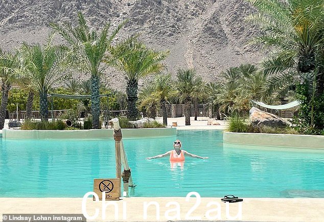 Paradise: Lohan 也分享了一张快照,她站在一个大游泳池里,游泳池里有许多棕榈树,身后是落基山脉景观