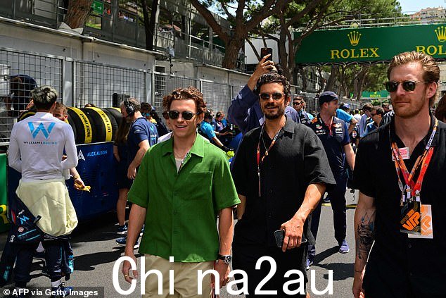 Paddock:Tom,穿着绿色衬衫和太阳镜,与银幕上的大腕 Orlando Bloom、David Harbor 和 Archie Madekwe 聊天时笑容满面