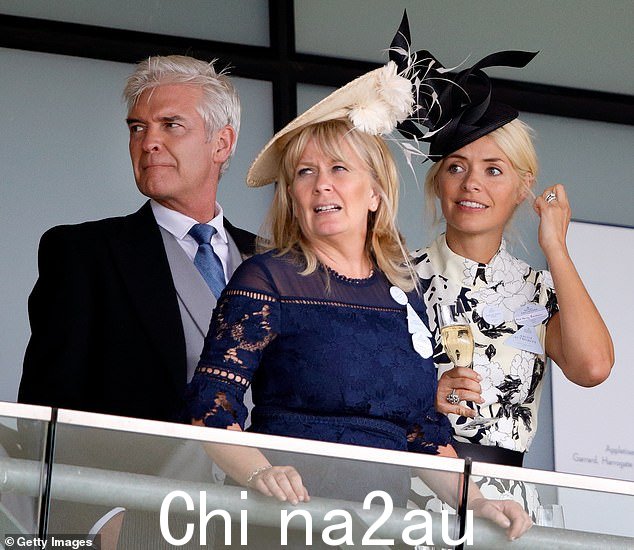 Holly Willoughby 今天是 Phillip Schofield 事件的中心人物,因为关于她是否知道她的联合主演的“欺骗”或者她是否也被主持人蒙蔽的问题仍然存在(如图所示) 2017 年与斯科菲尔德和他的妻子斯蒂芬妮·洛 (Stephanie Lowe) 在阿斯科特 (Ascot) Phillip Schofield 事件的后果,因为她是否知道她的联合主演的“欺骗”,或者她是否也被主持人蒙蔽了问题(2017 年在 Ascot 与 Schofield 和他的妻子 Stephanie Lowe 合影)</p> <img id =