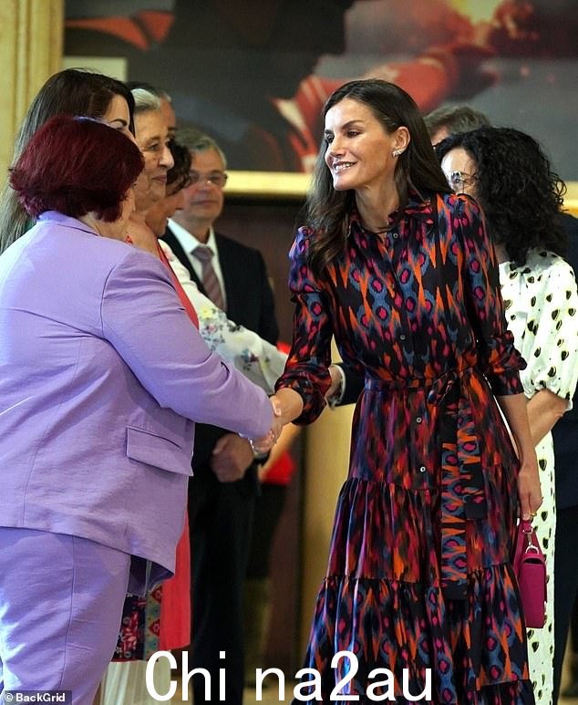 Letizia 在与今天在马德里举行的活动的与会者聊天时咧嘴一笑,因为她穿上了一件色彩缤纷的连衣裙